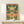 Minimalist botanical wall art with a monarch butterfly perched on cream-colored blooms surrounded by warm pink flowers and cool teal-green leaves in folk art style.