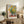 Sunflower arrangement with luminous petals in warm yellow and rust tones against cool sage greens and soft blues, evoking Impressionist light and tranquility.