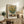 Warm impressionist floral painting showing sunflowers in a vessel with layered strokes in gold, cream, and soft blue, evoking peaceful elegance.