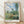 Impressionist landscape painting of Vetheuil village with poplar trees, green fields, and red poppies under a luminous blue sky with soft clouds, rendered in serene watercolor tones.