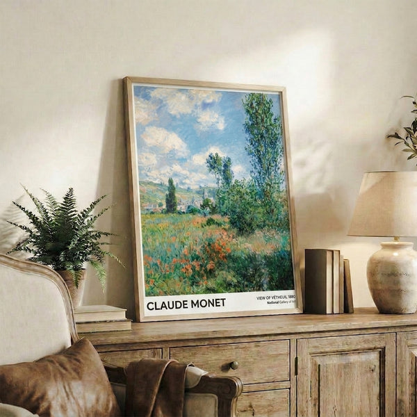 Framed watercolor landscape print of Vetheuil countryside with towering poplars, poppy-dotted meadows, and soft atmospheric clouds in muted greens, blues, and cream tones.