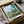 View of Vetheuil landscape painting in impressionist style showing peaceful countryside with poplars, red poppies, and village elements rendered in luminous sky blue and sage green hues.