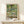 Framed impressionist artwork of Monet's famous Japanese bridge crossing calm waters dotted with water lilies, featuring a soft, hazy color palette of blues and ochres.