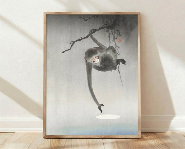 Japanese woodblock print depicting a playful monkey hanging from a branch, rendered in soft grays, blacks, and pale blue with minimalist composition and whimsical charm.