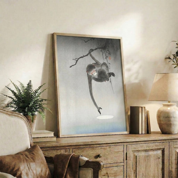 Ukiyo-e animal print mounted as wall art, depicting a monkey suspended from a branch in soft blacks and pale tones, evoking quiet contemplation and natural grace.