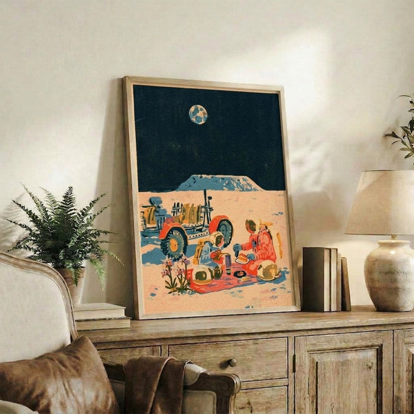 Framed retro space art showing adventurous astronauts gathered for a lunar picnic scene, combining sandy beige, deep teal, and burnt orange in a charmingly nostalgic composition.