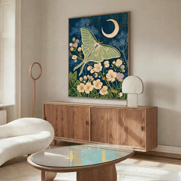 Vintage-style framed art print showcasing a luna moth in a moonlit garden of blooming flowers and ferns, rendered in soft greens, gold, and lavender tones.