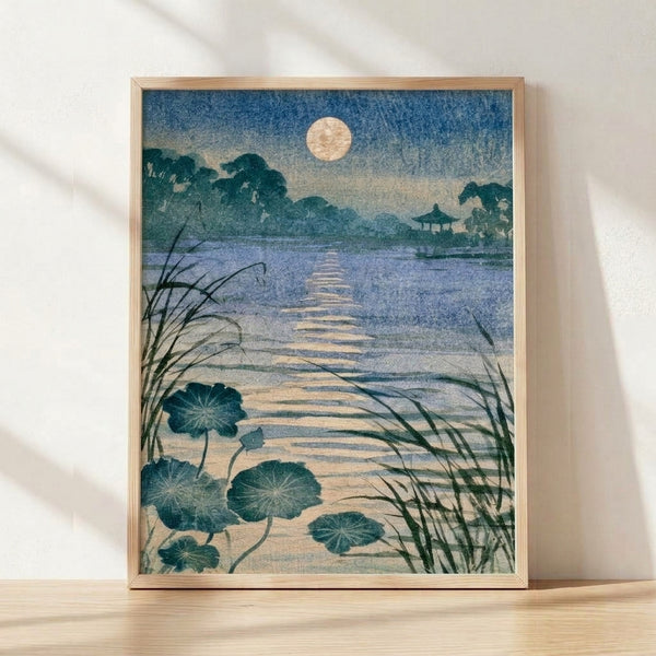 Serene Japanese woodblock-style poster depicting a moonlit lotus pond with a wooden bridge, pavilion, and reeds in slate blue, cream, and pale gold tones framed on a wall.