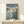 Contemplative Japandi art print depicting a tranquil water landscape with floating lotus flowers, a distant pagoda, and bamboo framed on a wall; soft color palette of deep teal, cream, and gold creates a meditative mood.