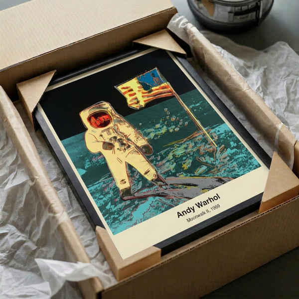 Framed pop art print depicting a spacesuit-clad figure against the moon in black, white, and silver tones, presenting a modern and iconic interpretation of the legendary space exploration achievement.