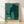 Minimalist framed poster featuring a mother woolly mammoth and baby elephant in silhouette, rendered in teal, sage green, and gold against a cream background, conveying tender protection and contemplative mood.