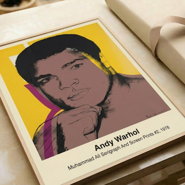 Muhammad Ali pop art poster in Warhol's distinctive technique, showcasing the legendary boxer's bold visage in striking yellow, red, and black hues framed on a wall.