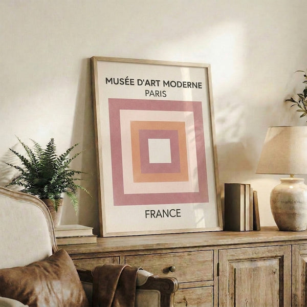 Abstract geometric print in soft mauve and peach tones with overlapping squares, displayed as a framed decorative poster.