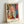 Sophisticated poster art depicting a woman in a mirrored interior scene with flowing lines in coral, ochre, and cream, accented by deep blue details in a modern sensual style.