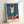 Framed poster artwork showing an odalisque in flowing fabric, artistic composition with warm ochre and soft pink hues balanced by rich blue accents in Art Nouveau aesthetic.