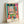 Contemplative abstract window scene with layered geometric shapes in fuchsia, ochre, and blue-green, evoking a lyrical seaside interior framed as wall art.