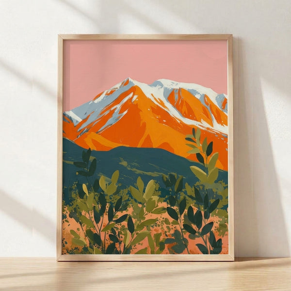 Bold mid-century modern landscape poster featuring layered desert mountain peaks in pink, orange, and teal with minimalist cactus silhouettes, warm serene aesthetic framed on wall.