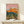 Minimalist desert sunset artwork with geometric mountain ranges in soft pink and orange tones, olive green accents, and stylized cacti in contemporary mid-century style.