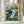 Folk art owl illustration in a warm knit hat amid flowing wildflower stems rendered in minimalist lines, using navy blue, golden accents, and forest green against cream, framed on wall.