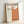 Mid-century minimalist gallery poster with simplified abstract sculptural composition in earthy terracotta, cream, and dark charcoal palette.