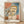 Abstract Bauhaus portrait poster in ochre, terracotta, and slate blue showing two geometric stylized figures representing Adam and Little Eve by Paul Klee, framed on a wall.