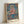 Framed abstract Bauhaus artwork depicting a boy wearing ornate dress, composed of angular shapes and muted palette with touches of vibrant pink and blue.