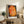 Framed abstract poster of a solitary figure beneath a pear tree, combining Bauhaus principles with warm orange, red, and ochre palette for a contemplative mood.