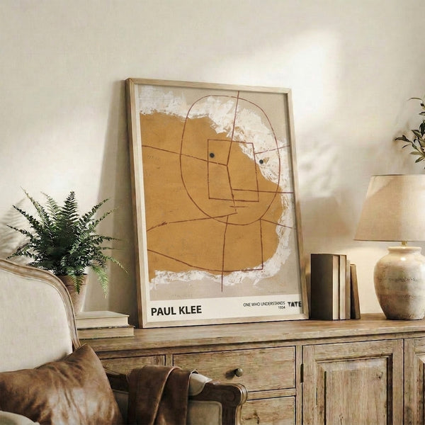 Contemplative Bauhaus artwork showing a stylized geometric head by Paul Klee, titled One Who Understands, in warm cream and sienna hues.