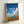 Framed minimalist poster depicting a vintage VW van set against rolling golden fields and a tranquil blue sky, ideal for contemplative spaces.