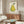 Calm wabi-sabi inspired wall art depicting a drowsy pear character in soft earth tones of cream, pale yellow, and sage green with delicate dark green foliage elements.