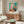 Framed abstract poster depicting a serene woman in pearlescent soft tones beside a window, rendered in minimalist form with an introspective, sophisticated mood.