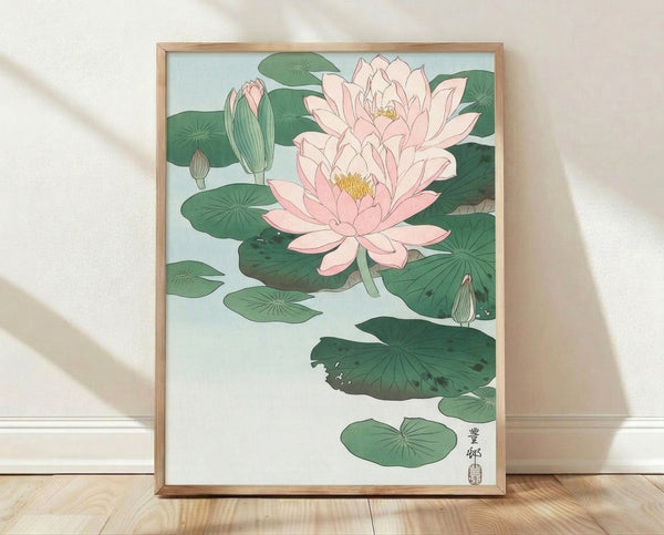 Serene Japanese woodblock-style poster featuring a pale pink water lily with sage green leaves and buds on cream background, framed on wall.