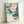 Japandi wall art showing a contemplative water lily composition with muted pink petals, pale and sage green leaves against cream, framed poster.