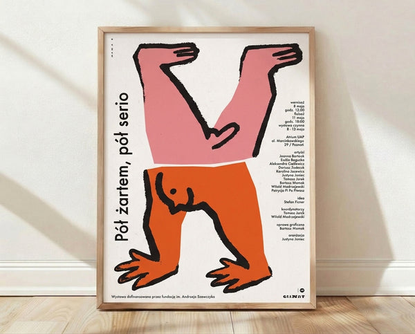 Bold Bauhaus exhibition poster featuring abstract pink and orange geometric figures with outstretched hands against black and cream, playful avant-garde design framed on wall.