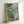 Magical framed poster showcasing a Ghibli-style scene with young travelers, a fantastical fish companion, and layered forest and ocean landscapes in calming seafoam and forest green hues.