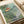 Whimsical Japandi wall art depicting children embarking on an enchanted boat journey surrounded by fantastical fish and forest scenery in cream, forest green, and coral hues.