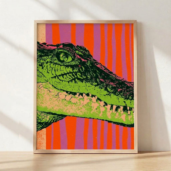 Bold pop art crocodile poster featuring vibrant lime green, hot orange, and mauve purple stripes against a black background, displayed as a framed print on a wall.