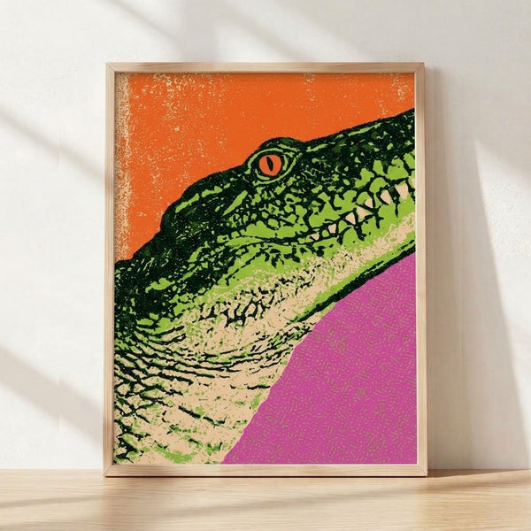 Bold pop art portrait of a colorful iguana with vibrant orange, lime green, and magenta tones against a cream background, framed as a modern retro poster on a wall.