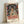 Woman's bust portrait in cream, green, and rust palette with impressionist brushwork and minimalist features, displayed as a framed poster.