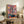 Wabi sabi aesthetic poster featuring a domestic window scene of potted plants and greenery rendered in retro colors: pink, yellow, teal, and cream with graphic black lines.
