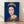 Pop art portrait of Queen Elizabeth II in bold dark blue tones, featuring stylized facial features and vibrant color blocking in the Reigning Queens series style, framed poster on wall.