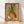 Whimsical watercolor folk art depicting a hare holding a wine glass beside a pear, rendered in warm olive, russet, and sage tones with cottagecore charm, displayed as a framed poster on a wall.