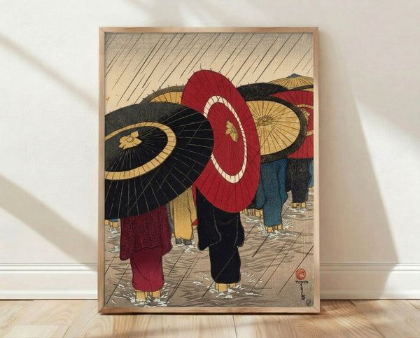 Japanese woodblock print depicting people with red and black umbrellas walking through rain on a wet street, rendered in traditional Showa-era style with cream and gold accents creating an atmospheric, melancholic mood.