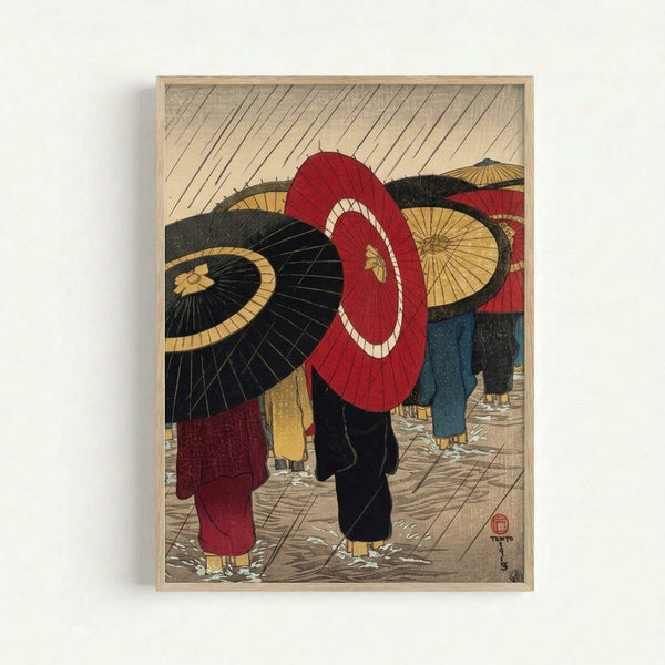 Framed traditional Japanese woodblock art showing a rainy urban scene with figures carrying umbrellas in red and deep blue tones against cream background, evoking contemplative melancholy.