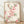 Delicate watercolor painting of peach blossoms with soft pink petals, green leaves, and brown stems on cream background, framed as botanical art print.