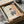 Playful whippet artwork in modern pop art style depicting the dog in aristocratic attire with a beret and ruff collar set before cream and teal wallpaper with warm gold accents, presented as a framed wall art print.