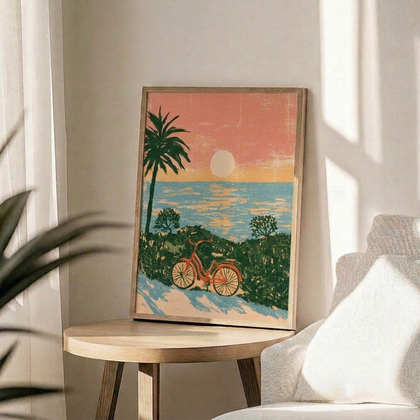 Nostalgic summery art print showing a solitary bicycle on sandy shore beneath a glowing sun with palm tree and ocean backdrop in soft coral, teal, and golden yellow hues.