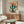 Warm-toned desert plant illustration with vibrant coral blooms and dark teal-green cacti in a retro botanical style, matted and framed as wall art.