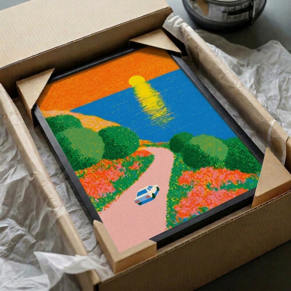 Framed retro travel poster artwork showcasing a breezy coastal journey with a classic car, ocean landscape, sunset colors of orange and pink, and wild yellow flowers along the route.