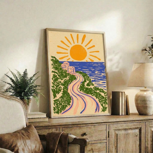 Framed vintage-style art print depicting a glowing golden sun above calm waters, a winding cream pathway, and coastal vegetation in forest green, with warm coral accents and a serene, retro aesthetic.
